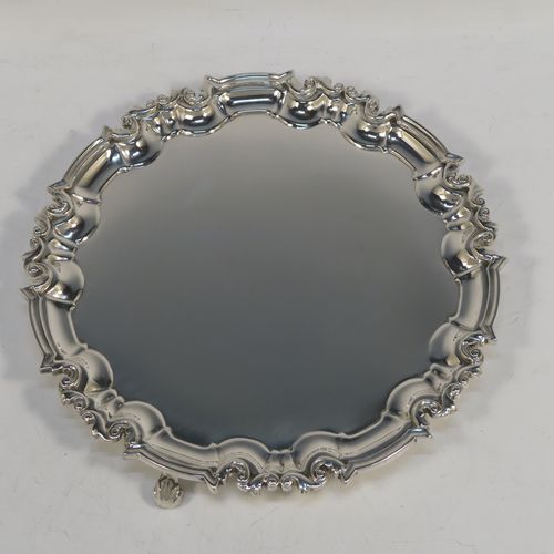 A very handsome Antique Victorian Sterling Silver round salver, having a plain burnished ground, an applied scroll border and sitting on three cast scroll feet. This beautiful antique silver salver was made by Edward Hutton of London in 1886. The dimensions of this fine hand-made antique silver salver are diameter 20 cms (8 inches), and it weighs approx. 422g (13.6 troy ounces).