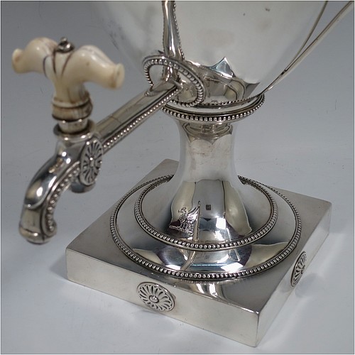 A very handsome Antique Georgian Neoclassical style Sterling Silver samovar, having a plain urn-shaped body, with pull-off lid and finial, two side-handles, an original spigot with bone handle, all with applied bead-edged borders, and all sitting on a pedestal foot with a square base. Please note that this piece has an unusual heating mechanism where the main body detaches from the foot allowing for the insertion of a heated piece of pig-iron. Made by John Denziloe of London in 1783. The dimensions of this fine hand-made antique silver samovar are height 52 cms (20.5 inches), width 33 cms (13 inches), and it weighs approx. 3,112g (100 troy ounces). Please note that this item is crested.