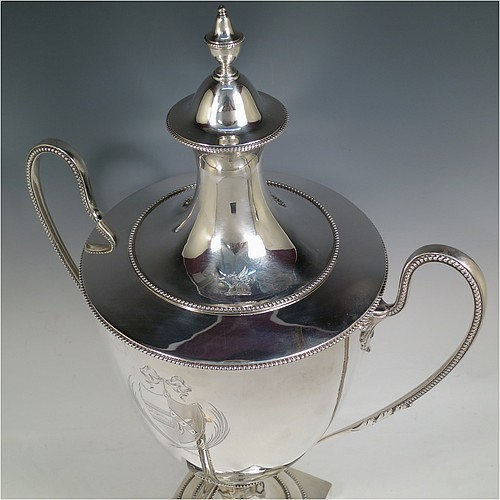 A very handsome Antique Georgian Neoclassical style Sterling Silver samovar, having a plain urn-shaped body, with pull-off lid and finial, two side-handles, an original spigot with bone handle, all with applied bead-edged borders, and all sitting on a pedestal foot with a square base. Please note that this piece has an unusual heating mechanism where the main body detaches from the foot allowing for the insertion of a heated piece of pig-iron. Made by John Denziloe of London in 1783. The dimensions of this fine hand-made antique silver samovar are height 52 cms (20.5 inches), width 33 cms (13 inches), and it weighs approx. 3,112g (100 troy ounces). Please note that this item is crested.