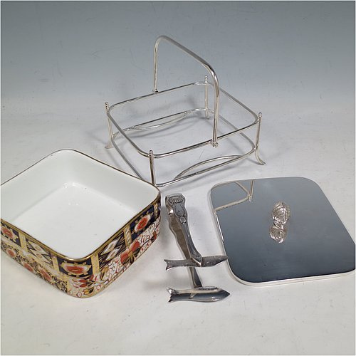 An Antique Victorian Silver Plated and fine China sardine dish, having a rectangular bone China body with hand-painted gold, blue, and orange scroll and floral decoration, all sitting in a plain wire-work galleried frame, a lift-off lid with cast conch shell finial, a plain handle, and all sitting on four wire-work feet, and with a pair of antique silver-plated sardine server tongs in the Kings pattern. The sardine dish made by James Dixon & Sons of Sheffield in ca. 1890. The dimensions of this fine hand-made antique silver-plated and bone China sardine dish are length 14 cms (5.5 inches), width 12 cms (4.75 inches), and height (excluding handles) 7 cms (2.75 inches).