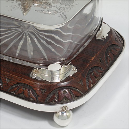 A very handsome Antique Victorian Silver Plated sardine dish, having a rectangular body with rounded corners, a cut-crystal liner sitting in a frame attached to an Oak wooden base with four ball feet, a lift-off lid with cast crossed sardines above hand-engraved floral decoration. Made in ca. 1890. The dimensions of this fine hand-made antique silver-plated sardine dish are length 18 cms (7 inches), width 15 cms (6 inches), and height 10 cms (4 inches).