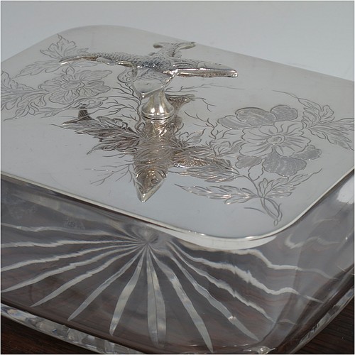 A very handsome Antique Victorian Silver Plated sardine dish, having a rectangular body with rounded corners, a cut-crystal liner sitting in a frame attached to an Oak wooden base with four ball feet, a lift-off lid with cast crossed sardines above hand-engraved floral decoration. Made in ca. 1890. The dimensions of this fine hand-made antique silver-plated sardine dish are length 18 cms (7 inches), width 15 cms (6 inches), and height 10 cms (4 inches).