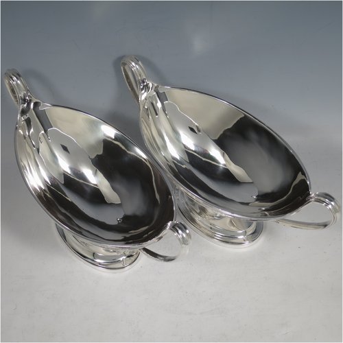 An Antique Georgian Sterling Silver pair of heavy sauce tureens, having oval neoclassical boat-shaped bodies with applied reeded borders, with cast reeded loop handles, and all sitting on cast oval pedestal feet. Made by Cornelius Bland y of London in 1792. The dimensions of this fine hand-made antique silver pair of sauce tureens are height 14 cms (5.5 inches), length 24.5 cms (9.75 inches), width 11 cms (4.25 inches), with a total weight of approx. 960g (31 troy ounces). Please note that both theses items are crested.