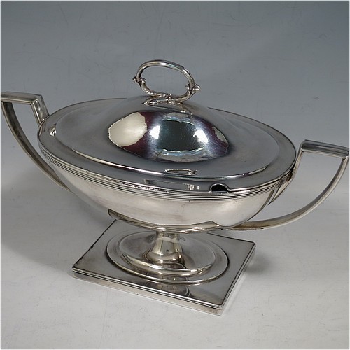 An Antique Georgian Old Sheffield silver-plated pair of Neoclassical sauce tureens, having oval boat-shaped bodies with applied reeded borders, with cast reeded side-handles, original domed lids with asparagus loop handles, and all sitting on pedestal feet with rectangular bases. Made in ca. 1790 in the Old Sheffield fused plate. The dimensions of this fine hand-made antique Old Sheffield silver plated pair of sauce tureens are height 14 cms (5.5 inches), length 23 cms (9 inches), and width 11 cms (4.25 inches).