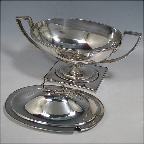 An Antique Georgian Old Sheffield silver-plated pair of Neoclassical sauce tureens, having oval boat-shaped bodies with applied reeded borders, with cast reeded side-handles, original domed lids with asparagus loop handles, and all sitting on pedestal feet with rectangular bases. Made in ca. 1790 in the Old Sheffield fused plate. The dimensions of this fine hand-made antique Old Sheffield silver plated pair of sauce tureens are height 14 cms (5.5 inches), length 23 cms (9 inches), and width 11 cms (4.25 inches).