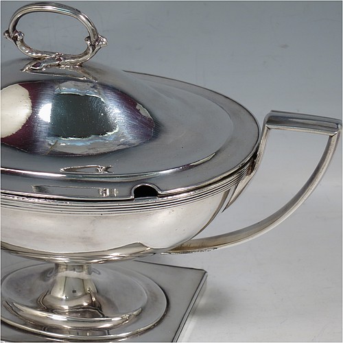 An Antique Georgian Old Sheffield silver-plated pair of Neoclassical sauce tureens, having oval boat-shaped bodies with applied reeded borders, with cast reeded side-handles, original domed lids with asparagus loop handles, and all sitting on pedestal feet with rectangular bases. Made in ca. 1790 in the Old Sheffield fused plate. The dimensions of this fine hand-made antique Old Sheffield silver plated pair of sauce tureens are height 14 cms (5.5 inches), length 23 cms (9 inches), and width 11 cms (4.25 inches).
