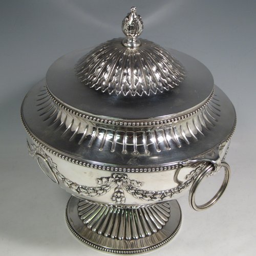 Antique Victorian sterling silver suite of soup and sauce tureens with covers, having round bodies with bead-edged borders, with hand-chased neoclassical style decoration, lift-off lids with anthemion leaves and cast floral finials, side handles with attached rings, and all sitting on pedestal feet. Made by Robert Hennell II of London in 1872. The dimensions of the fine larger silver tureen are height 27 cms (10.5 inches), diameter length 23 cms (9 inches), with a total weight of approx. 2,356g (76 troy ounces). Please note that these items are crested in one cartouche.