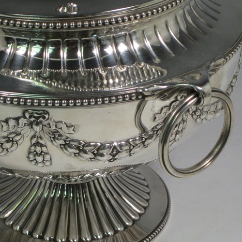 Antique Victorian sterling silver suite of soup and sauce tureens with covers, having round bodies with bead-edged borders, with hand-chased neoclassical style decoration, lift-off lids with anthemion leaves and cast floral finials, side handles with attached rings, and all sitting on pedestal feet. Made by Robert Hennell II of London in 1872. The dimensions of the fine larger silver tureen are height 27 cms (10.5 inches), diameter length 23 cms (9 inches), with a total weight of approx. 2,356g (76 troy ounces). Please note that these items are crested in one cartouche.