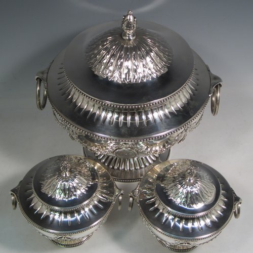 Antique Victorian sterling silver suite of soup and sauce tureens with covers, having round bodies with bead-edged borders, with hand-chased neoclassical style decoration, lift-off lids with anthemion leaves and cast floral finials, side handles with attached rings, and all sitting on pedestal feet. Made by Robert Hennell II of London in 1872. The dimensions of the fine larger silver tureen are height 27 cms (10.5 inches), diameter length 23 cms (9 inches), with a total weight of approx. 2,356g (76 troy ounces). Please note that these items are crested in one cartouche.