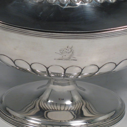 Antique Georgian sterling silver sauce tureen, having a neoclassical boat-shaped body with reeded borders and hand-chased half-fluted decoration, a lift-off cover with loop handle finial, all sitting on a pedestal foot. Made by Henry Chawner of London in 1795. Height 17 cms (6.75 inches), length 24 cms (9.5 inches), width 10 cms (4 inches). Total weight approx. 561g (18.1 troy ounces). Please note that this item is crested.