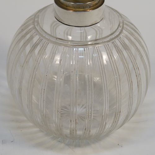 An elegant Antique Sterling Silver and hand-cut crystal large table scent bottle, having a plain round mount, a plain round hinged lid, an internal stopper, and a hand-cut crystal round main body with reeded decoration, and sitting on a flat base with a star-cut. This handsome antique silver and crystal scent bottle was made by William Comyns of Birmingham in 1913. The dimensions of this fine hand-made antique silver and crystal scent bottle are height 10 cms (4 inches), and diameter 9 cms (3.5 inches).   