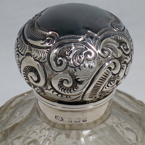 An Antique Edwardian Sterling Silver and hand-cut crystal table scent bottle, having a hand-chased round mount with floral decoration, a hinged lid, an internal stopper, and hand-cut crystal main body in the Hobnail pattern. Made by Hilliard & Thomason of Birmingham in 1906. The dimensions of this fine hand-made antique silver and crystal scent bottle are height 13 cms (5 inches), and diameter 9 cms (3.5 inches).    