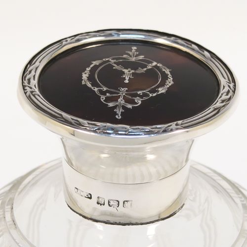 A very pretty Sterling Silver and inlaid tortoise-shell hand-cut crystal table scent bottle, having a plain round mount, a hinged lid with an inlaid tortoise-shell cover, an internal stopper, and hand-cut main body with reeding and star-cut decoration. This beautiful silver and crystal scent bottle was made by Hasset and Harper Ltd., of Birmingham in 1921. The dimensions of this fine hand-made silver and tortoise shell scent bottle are height 10 cms (4 inches), and diameter 9 cms (3.5 inches).