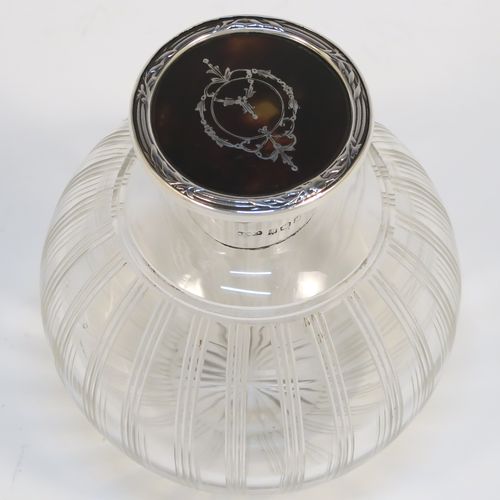 A very pretty Sterling Silver and inlaid tortoise-shell hand-cut crystal table scent bottle, having a plain round mount, a hinged lid with an inlaid tortoise-shell cover, an internal stopper, and hand-cut main body with reeding and star-cut decoration. This beautiful silver and crystal scent bottle was made by Hasset and Harper Ltd., of Birmingham in 1921. The dimensions of this fine hand-made silver and tortoise shell scent bottle are height 10 cms (4 inches), and diameter 9 cms (3.5 inches).