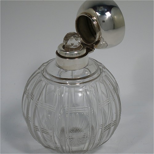 An Antique Sterling Silver and hand-cut crystal large table scent bottle, having a plain round mount, a hinged lid with an applied floral border and bands of engine-turned engraved decoration, an internal stopper, and a hand-cut crystal round main body with geometrical decoration. Made by Synyer and Beddoes of Birmingham in 1915. The dimensions of this fine hand-made antique silver and crystal scent bottle are height 11.5 cms (4.5 inches), and diameter 8 cms (3.25 inches).    