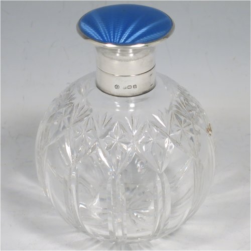A Sterling Silver and hand-cut crystal table scent bottle, having a plain round mount, a hinged lid with a blue enamelled top, an internal stopper, and hand-cut main body with reeding and star-cut  decoration. Made by Albert Carter of Birmingham in 1926. The dimensions of this fine hand-made silver and enamelled scent bottle are height 11 cms (4.25 inches), and diameter 9 cms (3.5 inches).    