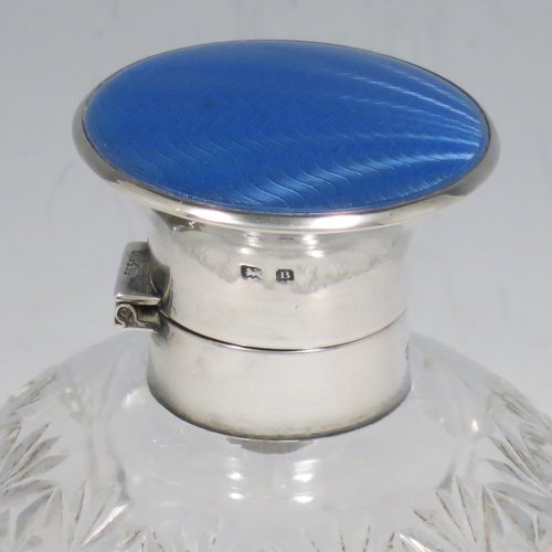 A Sterling Silver and hand-cut crystal table scent bottle, having a plain round mount, a hinged lid with a blue enamelled top, an internal stopper, and hand-cut main body with reeding and star-cut  decoration. Made by Albert Carter of Birmingham in 1926. The dimensions of this fine hand-made silver and enamelled scent bottle are height 11 cms (4.25 inches), and diameter 9 cms (3.5 inches).    