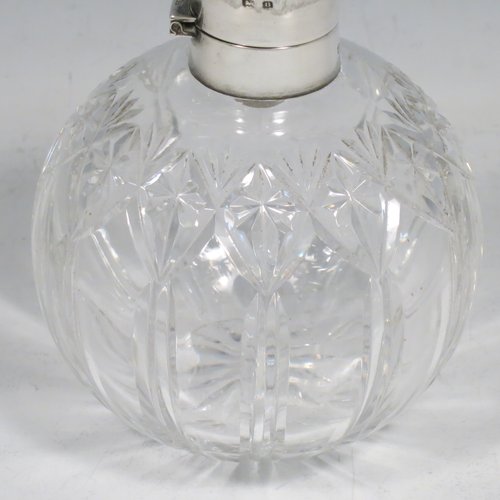 A Sterling Silver and hand-cut crystal table scent bottle, having a plain round mount, a hinged lid with a blue enamelled top, an internal stopper, and hand-cut main body with reeding and star-cut  decoration. Made by Albert Carter of Birmingham in 1926. The dimensions of this fine hand-made silver and enamelled scent bottle are height 11 cms (4.25 inches), and diameter 9 cms (3.5 inches).    