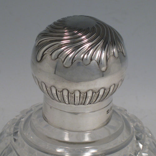 Antique Victorian sterling silver and hand-cut crystal large table scent bottle, having a hand-chased round mount with swirl-flute decoration, a hinged lid, an internal stopper, and hobnail cut main body with a shield-shaped cartouche. Made by James Dixon and Sons of Sheffield in 1901. The dimensions of this fine hand-made scent bottle are height 15 cms (6 inches), and diameter 11 cms (4.25 inches).   