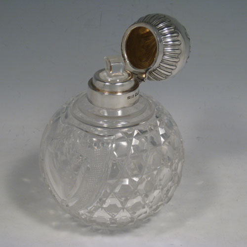 Antique Victorian sterling silver and hand-cut crystal large table scent bottle, having a hand-chased round mount with swirl-flute decoration, a hinged lid, an internal stopper, and hobnail cut main body with a shield-shaped cartouche. Made by James Dixon and Sons of Sheffield in 1901. The dimensions of this fine hand-made scent bottle are height 15 cms (6 inches), and diameter 11 cms (4.25 inches).   