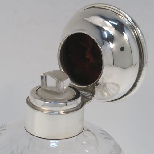 A very beautiful Sterling Silver and inlaid tortoise-shell hand-cut crystal table scent bottle, having a plain round mount, a hinged lid with an inlaid tortoise-shell cover, an internal stopper, a round main body with frosted cut floral hand-engraving and bands of reeded decoration, and siting on a flat base with hand-engraved star-cut work. This pretty silver and crystal scent bottle was made by Henry Matthew of Birmingham in 1928. The dimensions of this fine hand-made silver and tortoise shell scent bottle are height 14 cms (5.5 inches), and diameter 8.5 cms (3.3 inches).