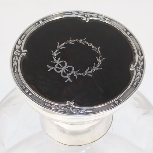 A very beautiful Sterling Silver and inlaid tortoise-shell hand-cut crystal table scent bottle, having a plain round mount, a hinged lid with an inlaid tortoise-shell cover, an internal stopper, a round main body with frosted cut floral hand-engraving and bands of reeded decoration, and siting on a flat base with hand-engraved star-cut work. This pretty silver and crystal scent bottle was made by Henry Matthew of Birmingham in 1928. The dimensions of this fine hand-made silver and tortoise shell scent bottle are height 14 cms (5.5 inches), and diameter 8.5 cms (3.3 inches).