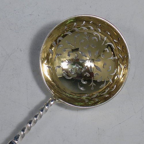 An Antique Victorian Sterling Silver and gold-gilt serving spoon set, consisting of a pair of serving spoons and a sugar sifting ladle, having cast handles with twisted stems and Lyre shaped terminals, and with gold-gilt bowls, and all sitting in an original olive green satin and velvet-lined presentation box. Made by Holland, Aldwinckle, & Slater of London in 1895. The dimensions of this fine hand-made set of antique silver serving spoons are length 17 cms (6.75 inches), and they weigh a total of approx. 154g (5 troy ounces).