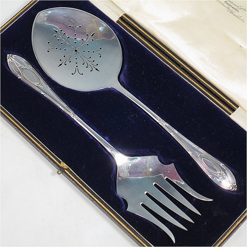 An Antique Sterling Silver serving spoon and fork, having hand-chased neoclassical pattern handles, the spoon with a hand-pierced blade, and the fork with five hand-cut tines, and all sitting in their original cream satin and dark blue velvet-lined presentation box. Made by Roberts & Belk of Sheffield in 1913. The dimensions of this fine hand-made antique pair of serving spoon and fork are length 24cms (9.5 inches), and they weigh a total of approx. 222g (7.2 troy ounces).