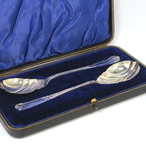 A beautiful pair of Antique Edwardian Sterling Silver serving spoons, having handles with double-struck floral and scroll-work in a Louis style pattern handles, and fluted oval bowls with a gold-gilt wash and hand-engraved floral work, all in their original dark blue satin and velvet-lined presentation box. These wonderful silver serving spoons were made by Thomas Brabury of Sheffield in 1910. The dimensions of this fine hand-made pair of antique silver serving spoons are length 19cms (7.5 inches), and they weigh a total of approx. 97g (3 troy ounces).   