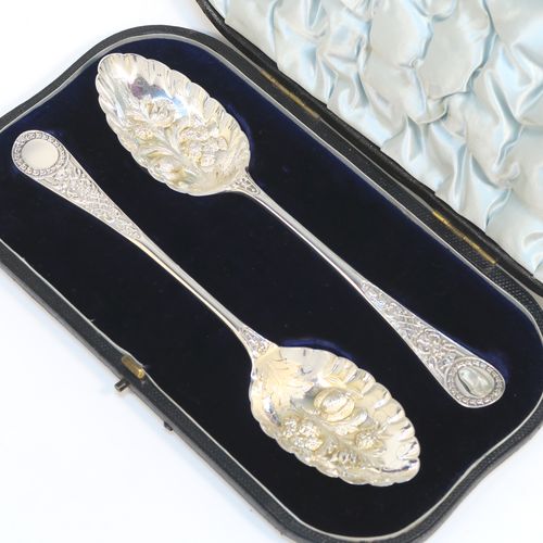 A very pretty pair of Antique Victorian Sterling Silver berry serving spoons, having hand-chased handles with floral decoration, and hand-chased bowls with fluted and fruit decoration, all in their original light blue satin and dark blue velvet-lined presentation box. These beautiful silver serving spoons were made by William Hutton and Sons of London in 1893. The dimensions of this fine hand-made pair of antique silver berry spoons are length 22cms (8.75 inches), and they weigh a total of approx. 146g (4.7 troy ounces).   