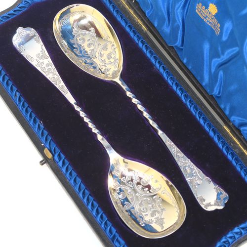 An extremely pretty pair of Antique Victorian Sterling Silver berry serving spoons, having hand-engraved handles and bowls with floral and scroll decoration, the bowls with a gold-gilt wash, and the handles with twisted middle sections, all in their original blue satin and velvet-lined presentation box. These beautiful silver serving spoons were made by the Atkin Brothers of Sheffield in 1900. The dimensions of this fine hand-made pair of antique silver berry spoons are length 21cms (8.3 inches), and they weigh a total of approx. 116g (3.7 troy ounces).  