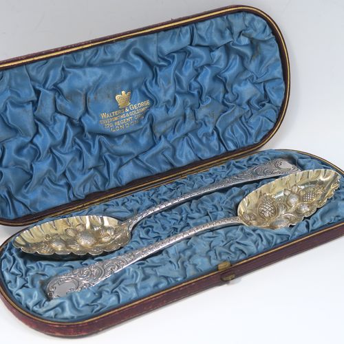 A very pretty pair of Antique Georgian Sterling Silver berry serving spoons, having hand-chased handles with floral and scroll decoration, and hand-chased bowls with gold-gilt fruit decoration, all in their original light blue satin-lined presentation box. These beautiful silver serving spoons were made by William Eley of London in 1782. The dimensions of this fine hand-made pair of antique silver berry spoons are length 22.5cms (8.75 inches), and they weigh a total of approx. 124g (4 troy ounces).   