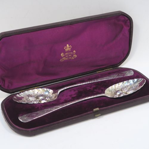 A very pretty pair of Antique Georgian Sterling Silver berry serving spoons, having hand-chased handles with geometric and floral decoration, and hand-chased bowls with fluted and fruit decoration, all in their original purple satin and velvet-lined presentation box. These beautiful silver serving spoons were made by George Burrows of London in 1793. The dimensions of this fine hand-made pair of antique silver berry spoons are length 22.5cms (8.75 inches), and they weigh a total of approx. 109g (3.5 troy ounces).   