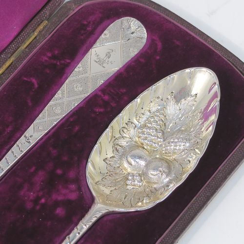 A very pretty pair of Antique Georgian Sterling Silver berry serving spoons, having hand-chased handles with geometric and floral decoration, and hand-chased bowls with fluted and fruit decoration, all in their original purple satin and velvet-lined presentation box. These beautiful silver serving spoons were made by George Burrows of London in 1793. The dimensions of this fine hand-made pair of antique silver berry spoons are length 22.5cms (8.75 inches), and they weigh a total of approx. 109g (3.5 troy ounces).   