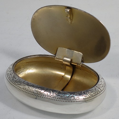 A very pretty Antique Edwardian Sterling Silver tobacco box, having an oval body, with hand-engraved floral and scroll decoration, a vacant cartouche, a squeeze-action sprung hinged lid, and a gold-gilt interior. Made by James Round of Birmingham in 1910. The dimensions of this fine hand-made antique silver tobacco box are length 8 cms (3.25 inches), width 6 cms (2.3 inches), and it weighs approx. 78g (2.5 troy ounces).