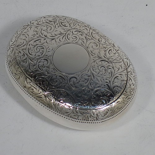 A very pretty Antique Edwardian Sterling Silver tobacco box, having an oval body, with hand-engraved floral and scroll decoration, a vacant cartouche, a squeeze-action sprung hinged lid, and a gold-gilt interior. Made by James Round of Birmingham in 1910. The dimensions of this fine hand-made antique silver tobacco box are length 8 cms (3.25 inches), width 6 cms (2.3 inches), and it weighs approx. 78g (2.5 troy ounces).