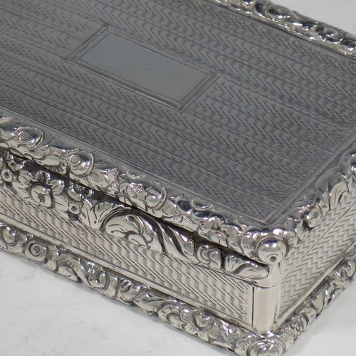 An Antique Georgian Sterling silver large and heavy snuff box, having a rectangular body with engine-turned decoration, with applied cast foliate thumb-piece and borders, and a gold-gilt interior. Made by John Bettridge of Birmingham in 1825. The dimensions of this fine hand-made antique silver snuff box are length 8 cms (3.25 inches), width 5 cms (2 inches), depth 2.5 cms (1.0 inches), and it weighs approx. 156g (5 troy ounces).