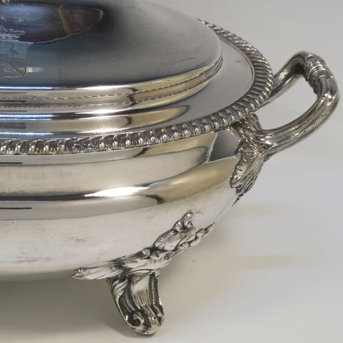 A very handsome Antique Georgian Old Sheffield Plated soup tureen in a Regency style, having an oval plain bellied body with an applied gadroon border, a domed pull-off cover with a cast anthemion leaf handle, with two cast anthemion leaf side handles, and sitting on four cast scroll feet with floral shoulders. This elegant antique Old Sheffield Plated soup tureen and cover was made in ca. 1815. The dimensions of this fine hand-made antique Old Sheffield soup tureen are length (across handles), width 23.5 cms (9.25 inches), height 25.5 cms (10 inches). Please note that this antique Georgian Regency soup tureen is crested on the cover.