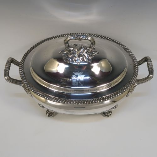 A very handsome Antique Georgian Old Sheffield Plated soup tureen in a Regency style, having an oval plain bellied body with an applied gadroon border, a domed pull-off cover with a cast anthemion leaf handle, with two cast anthemion leaf side handles, and sitting on four cast scroll feet with floral shoulders. This elegant antique Old Sheffield Plated soup tureen and cover was made in ca. 1815. The dimensions of this fine hand-made antique Old Sheffield soup tureen are length (across handles), width 23.5 cms (9.25 inches), height 25.5 cms (10 inches). Please note that this antique Georgian Regency soup tureen is crested on the cover.