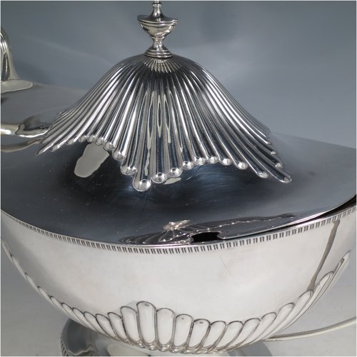 An Antique Edwardian Sterling silver soup tureen, having a pull-off lid with an urn-shaped finial and cut-out slot for a ladle, with hand-chased half-fluted decoration, applied gadroon borders, two reeded scroll side-handles, and all sitting on a pedestal foot. Made by Mappin & Webb of Sheffield in 1905. The dimensions of this fine hand-made antique silver soup tureen and cover are height 25 cms (9.75 inches), length including handles 39.5 cms (15.5 inches), width 21.5 cms (8.5 inches), and it weighs approx. 1,779 (57 troy ounces).