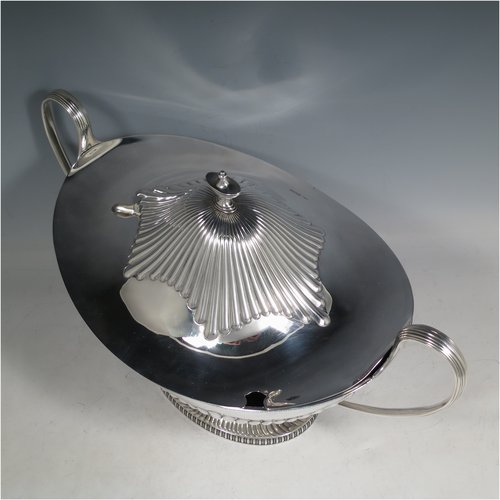 An Antique Edwardian Sterling silver soup tureen, having a pull-off lid with an urn-shaped finial and cut-out slot for a ladle, with hand-chased half-fluted decoration, applied gadroon borders, two reeded scroll side-handles, and all sitting on a pedestal foot. Made by Mappin & Webb of Sheffield in 1905. The dimensions of this fine hand-made antique silver soup tureen and cover are height 25 cms (9.75 inches), length including handles 39.5 cms (15.5 inches), width 21.5 cms (8.5 inches), and it weighs approx. 1,779 (57 troy ounces).