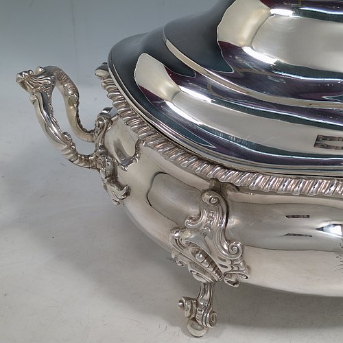 An Antique Early Victorian Sterling Silver soup tureen in a Regency style, having an oval bellied body with an applied wavy gadroon border, a domed pull-off cover with a cast pumpkin and leaf handle, with two cast scroll and shell side handles, and sitting on four cast scroll feet with floral shoulders. Made by William Moulson of London in 1840. The dimensions of this fine hand-made antique silver soup tureen and cover are length 43 cms (17 inches), height 25.5 cms (10 inches), width 24 cms (9.5 inches), and it weighs approx. 3,195g (103 troy ounces). Please note that this antique Victorian silver soup tureen is crested on the main body and cover.