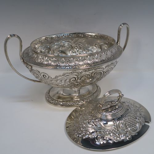 A beautiful Antique Victorian Silver Plated soup tureen, having a hand-chased oval body with floral and scroll decoration, a pull-off cover with cast finial handle and soup ladle cut-out, together with two reeded loop side-handles, and all sitting on a pedestal foot. This handsome silver-plated soup tureen and cover was made by Henry Cook and Co., of Sheffield in ca. 1880. The dimensions of this fine hand-made antique silver-plated soup tureen and cover are height 27 cms (10.5 inches), and width (across handles) 37 cms (14.5 inches).