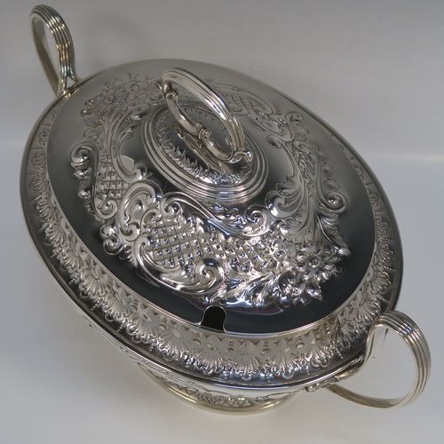 A beautiful Antique Victorian Silver Plated soup tureen, having a hand-chased oval body with floral and scroll decoration, a pull-off cover with cast finial handle and soup ladle cut-out, together with two reeded loop side-handles, and all sitting on a pedestal foot. This handsome silver-plated soup tureen and cover was made by Henry Cook and Co., of Sheffield in ca. 1880. The dimensions of this fine hand-made antique silver-plated soup tureen and cover are height 27 cms (10.5 inches), and width (across handles) 37 cms (14.5 inches).