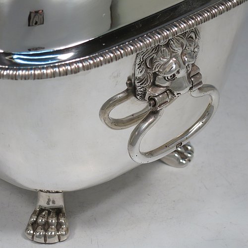 An Antique Georgian Sterling Silver soup tureen, having a plain rectangular body with rounded corners, a pull-off lid cover with an asparagus loop handle, with applied gadroon borders, two cast lion-mask loop side handles, and all sitting on four cast lions-paw feet. Made by William Bennett of London in 1805. The dimensions of this fine hand-made antique silver soup tureen and cover are height 21 cms (8.25 inches), length 28 cms (11 inches), width 20 cms (8 inches), and it weighs approx. 1,860 (60 troy ounces). Please note that this antique soup tureen is crested on one side.