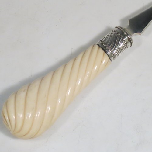 An Antique Victorian Sterling Silver and Ivory handled stilton cheese scoop, having a hand-cut spirally fluted handle, a hand-chased swirl-fluted ferrule, and a twisted stem with plain scoop. Made by William Hutton of London in 1899. The dimensions of this fine hand-made antique silver stilton cheese scoop are length 24 cms (9.5 inches).