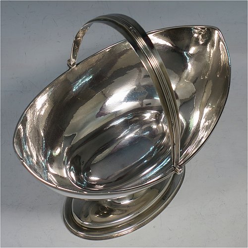 An Antique Georgian Sterling Silver sugar basket, having a plain oval bellied body, with applied reeded borders, a hinged and reeded swing-handle, and sitting on a pedestal foot. Made by Peter & Anne Bateman of London in 1798. The dimensions of this fine hand-made antique silver sugar basket are height (inc. handle) 18 cms (7 inches), length 16.6 cms (6.5 inches), and it weighs approx. 215g (7 troy ounces).