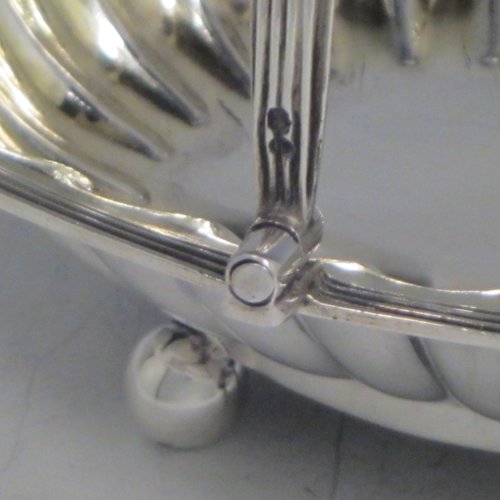 Antique Georgian sterling silver sugar or sweetmeat basket, having an oval body, with hand-chased and fluted decoration, an applied reeded border, a gold-gilt interior, a reeded swing-handle, and sitting on four ball feet. Made by William Bateman of London in 1815. The dimensions of this fine hand-made silver sugar basket are height 12.5 cms (5 inches), length 16 cms (6.25 inches), width 14 cms (5.5 inches), and it weighs approx. 174g (5.6 troy ounces).