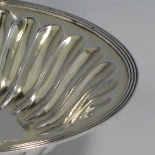Antique Georgian sterling silver sugar or sweetmeat basket, having an oval body, with hand-chased and fluted decoration, an applied reeded border, a gold-gilt interior, a reeded swing-handle, and sitting on four ball feet. Made by William Bateman of London in 1815. The dimensions of this fine hand-made silver sugar basket are height 12.5 cms (5 inches), length 16 cms (6.25 inches), width 14 cms (5.5 inches), and it weighs approx. 174g (5.6 troy ounces).