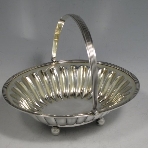 Antique Georgian sterling silver sugar or sweetmeat basket, having an oval body, with hand-chased and fluted decoration, an applied reeded border, a gold-gilt interior, a reeded swing-handle, and sitting on four ball feet. Made by William Bateman of London in 1815. The dimensions of this fine hand-made silver sugar basket are height 12.5 cms (5 inches), length 16 cms (6.25 inches), width 14 cms (5.5 inches), and it weighs approx. 174g (5.6 troy ounces).
